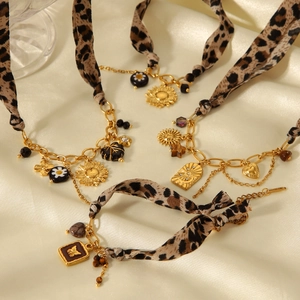 Detailed view of leopard print ribbon bracelet with gold pendants on silk background