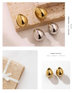 Close-up of polished gold and silver water-drop earrings on a minimalist stone base