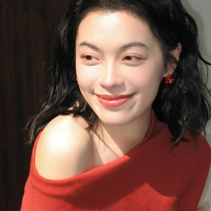 Elegant red flower stud earrings with gold center worn by model in a stylish red outfit