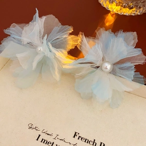 Detailed close-up of blue gradient mesh flower earrings with central pearl accents