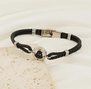 Detail of nautical compass bracelet with anchor emblem on white stone background