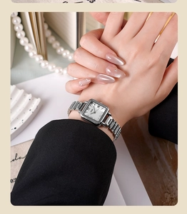 Gros plan d'une montre GEDI carrée en argent avec chiffres romains sur un poignet féminin