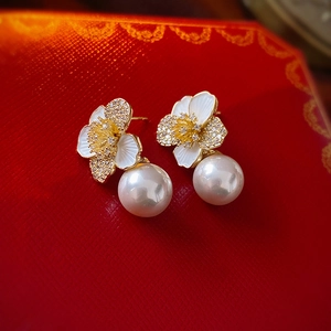 Macro view of gold flower earrings with white petals, small diamonds and pearls