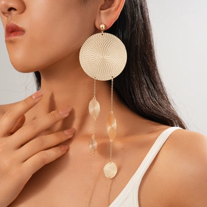 Close-up of gold metal drop earrings with woven texture and leaf-shaped pendants on model