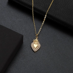 Detailed view of a gold heart crown pendant with red ruby and zircons on black leather