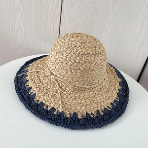 Détail d'un chapeau en raphia avec bordure au crochet bleu marine et nœud en paille fine