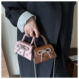 Detailed shot of mini PU handbags with rhinestone bows and silver metal chain straps