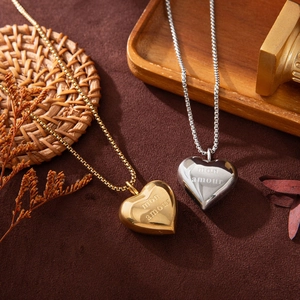 Macro shot of gold and silver heart necklaces with Mon Amour engraving on velvet background