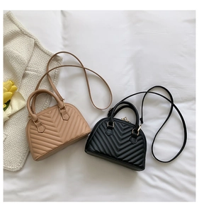 Close-up of diamond quilted shell bags in black and beige with gold hardware details