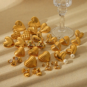 Collection of golden heart earrings with striped texture and pearl accents on beige fabric