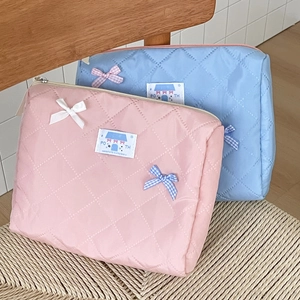 Detail of quilted waterproof cosmetic bags with decorative bows and woven labels