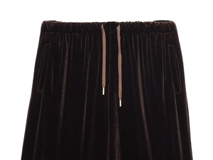 Detail of dark brown velvet trousers featuring an elastic waistband and gold tipped drawstrings