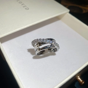 Detail of silver triple-layer crossover ring with cubic zirconia in a white jewelry box