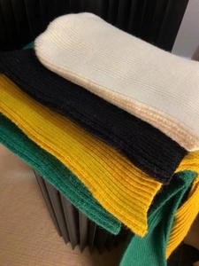 Detail of ribbed knit texture in beige, black, yellow, and green winter yarn fabric