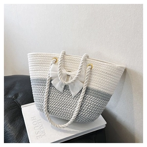 Close-up of handmade woven tote bag with grey-white patterns and white bow ribbon