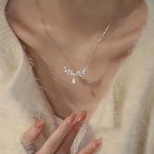 Close-up of leaf-shaped silver necklace with diamonds and teardrop zircon pendant