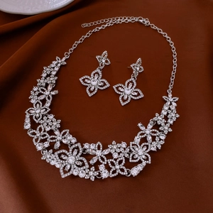 Detailed view of silver flower necklace and earrings set with sparkling rhinestones