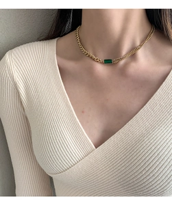 Detail of double-layer gold chain necklace with rectangular emerald green gemstone