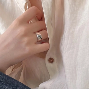 Close-up of minimalist silver band ring with round zebra stone on hand with linen shirt