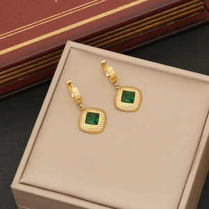 Elegant gold square earrings with emerald green gemstones on a beige jewelry box