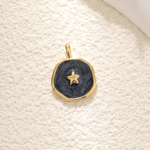 Gold pendant with dark blue enamel, gold star accent on beige textured background
