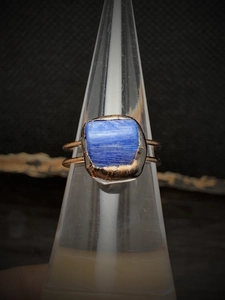 Macro shot of rectangular blue raw gemstone on a gold adjustable ring band