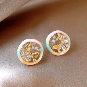 Macro view of gold round butterfly stud earrings with colorful enamel and crystals