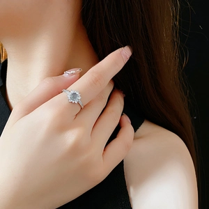 Detailed view of silver flower ring with blue gemstone and zircon on finger