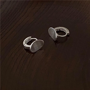 Detailed view of 925 sterling silver brushed oval earrings on a rustic wood surface
