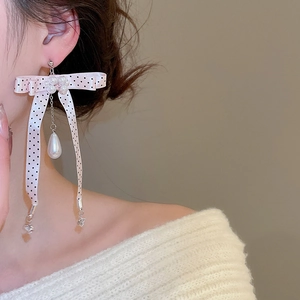 Detailed view of pink polka dot bow earrings with floral pearl and teardrop pendant