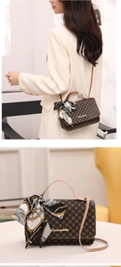 Classic brown monogram crossbody bag with silk scarf handle on a model and table