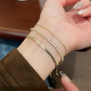 Close-up of three-piece gold snake chain and zircon bracelet set on a model's wrist