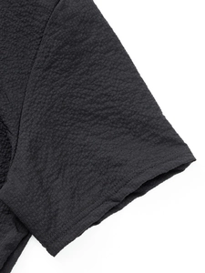 Close-up of the black polo shirt featuring textured waffle knit fabric and premium seams