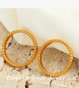 Close-up of 18k gold gear rings with square stud engraving on silk and stone
