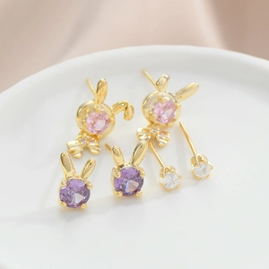 Cute golden rabbit stud earring set with purple and pink crystals on white porcelain