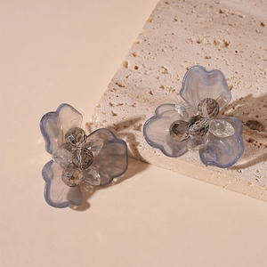 Macro shot of sweet translucent grey-blue resin flower hoop earrings on stone