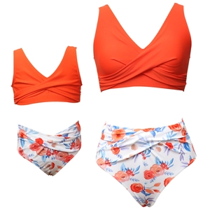 Detail of mother and daughter matching floral bikinis with orange crossover V-neck tops