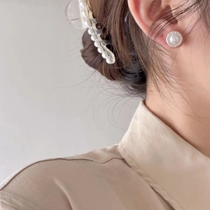 Close-up of elegant pearl stud earrings with silver edges and matching hair clip on model