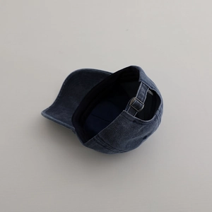 Detail view of washed denim baseball cap with an adjustable metal buckle on the back