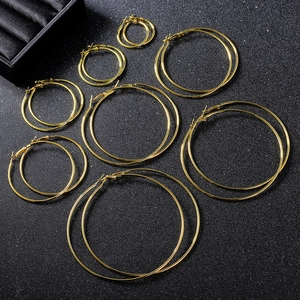 Various sizes of golden hoop earrings displayed on black textured surface with jewelry box