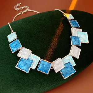Macro view of blue and white enamel square pendants on a silver chain necklace