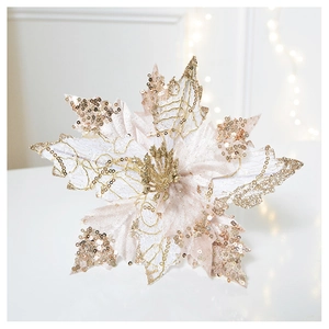 Detailed close-up of champagne gold glitter Christmas flower on white surface with bokeh lights