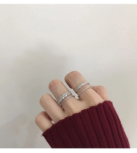Macro shot of silver-toned stacked rings featuring zircon pavé settings on female model