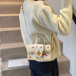 Elegant beige square handbag with cherry print, golden floral clasp and woven handle