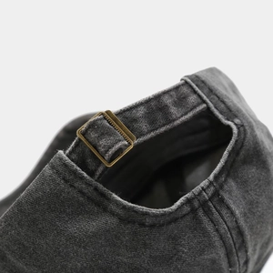 Detail of adjustable brass buckle and washed denim fabric on the back of a baseball cap