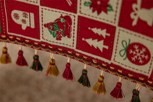 Close-up of Christmas table runner with snowflake patterns and colorful hanging tassels