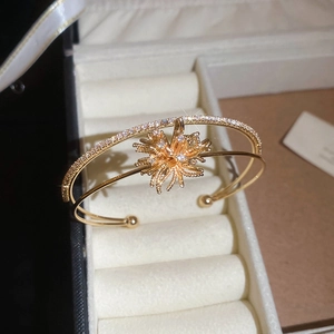 Macro shot of gold double-layer open bangle with zircon firework motif and ball ends