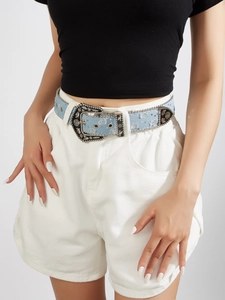 Detail of light blue denim belt with retro silver floral buckle worn on model