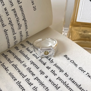 Irregular silver textured ring with yellow rectangular gemstone on vintage book pages