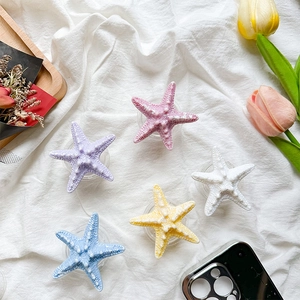 Detailed view of colorful starfish phone grips in pastel tones on a white cloth